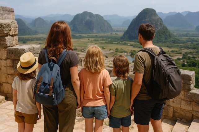 Family of four worldschooling, overlooking a scenic mountain landscape with lake and valley in the distance.
